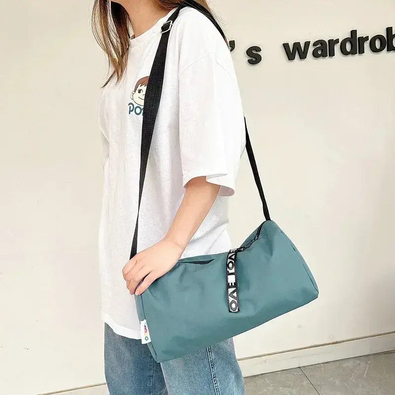 Woman carrying a teal women's gym bag, showcasing its stylish design and practicality for fitness enthusiasts.